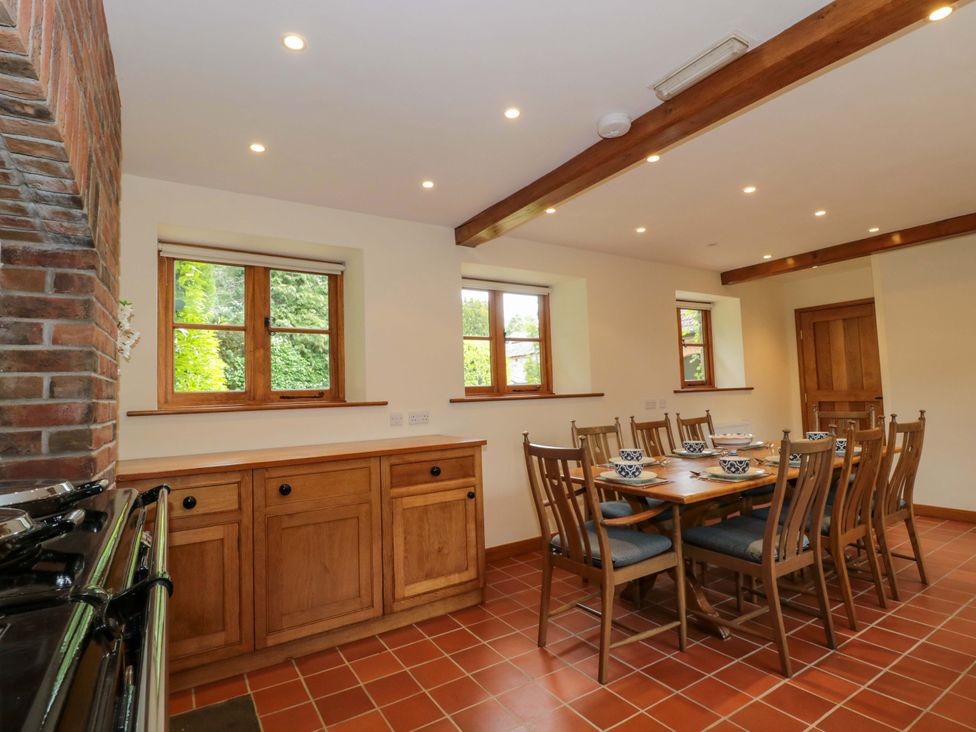 A kitchen with a dining table and wooden cabinets at Stowey Mead Stables Bishop Sutton