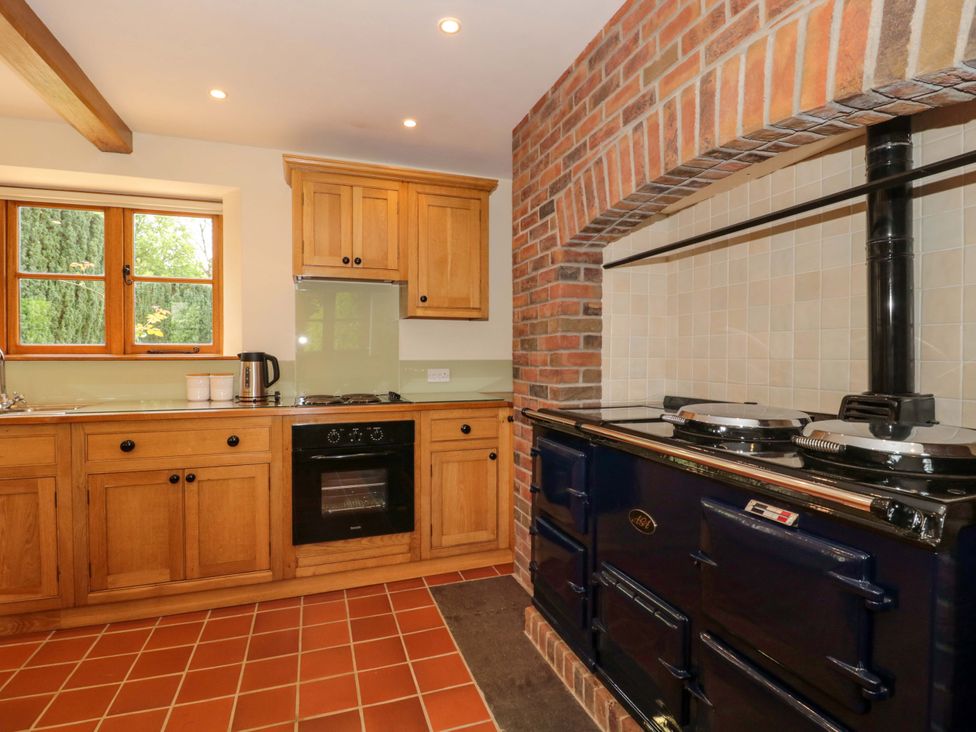 A kitchen with wooden cabinets and an oven at Stowey Mead Stables in Bishop Sutton