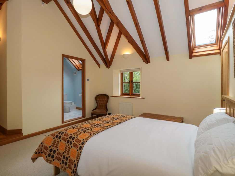 A bedroom with a bed and a chair at Stowey Mead Stables in Bishop Sutton