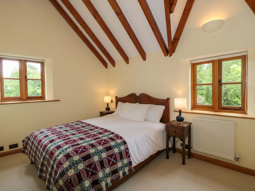 A bedroom with a bed and windows at Stowey Mead Stables in Bishop Sutton