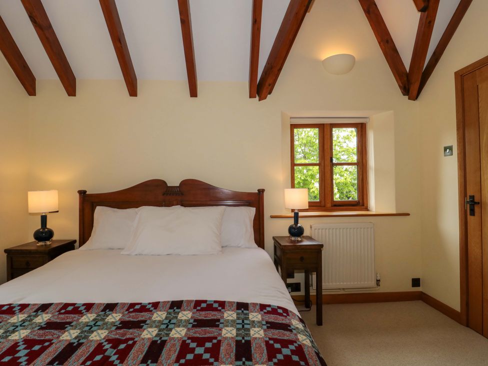 A bedroom with a bed and nightstands at Stowey Mead Stables Bishop Sutton