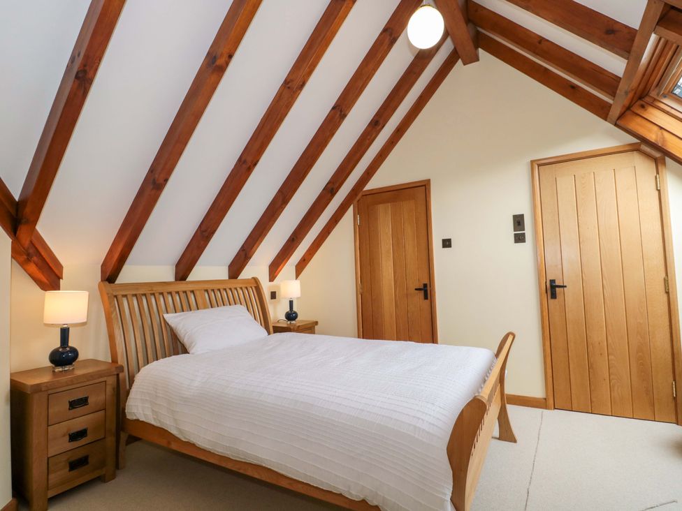 A bedroom with a bed and wooden furniture at Stowey Mead Stables, Bishop Sutton