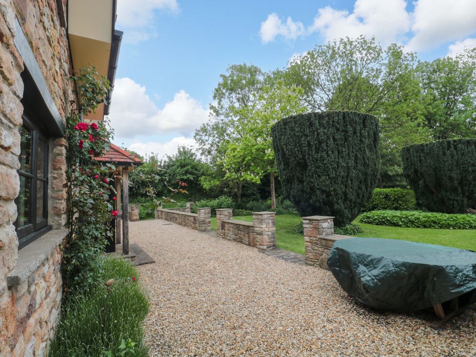 A garden with gravel pathway and stone walls at Stowey Mead Stables Bishop Sutton