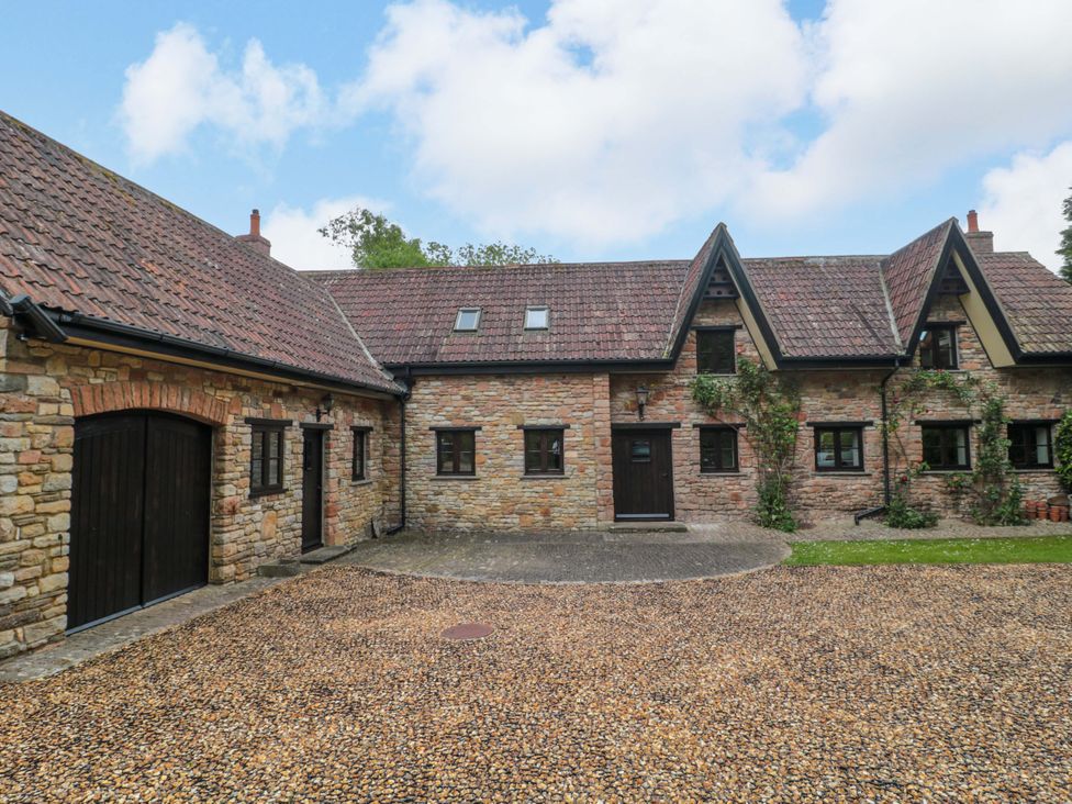 A brick building with gravel driveway at Stowey Mead Stables in Bishop Sutton