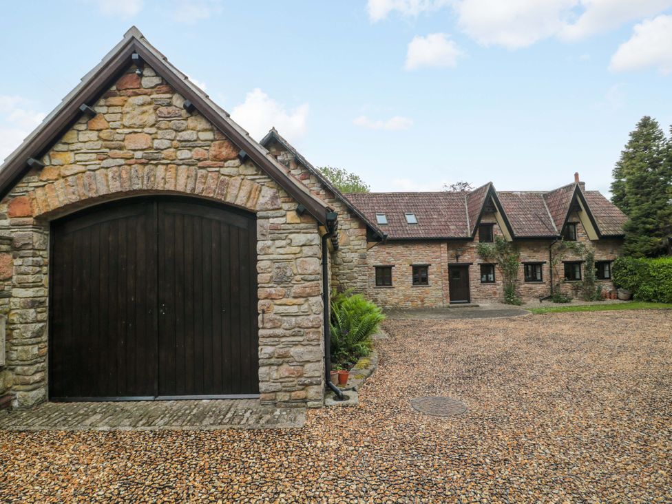 An outdoor view of a stone garage and house at Stowey Mead Stables in Bishop Sutton