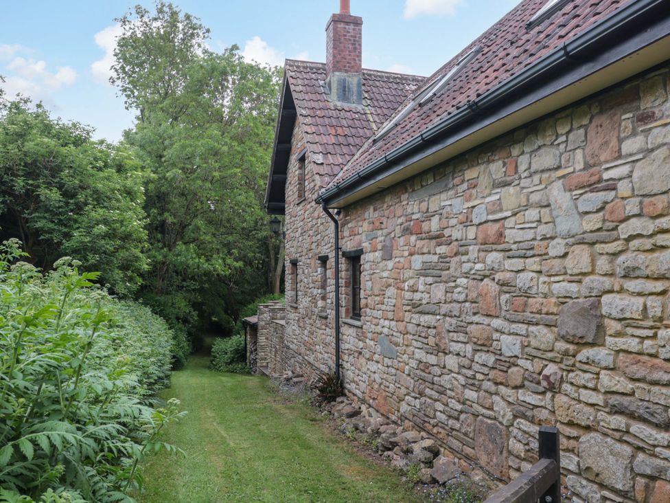 A stone building with a pathway and greenery at Stowey Mead Stables Bishop Sutton