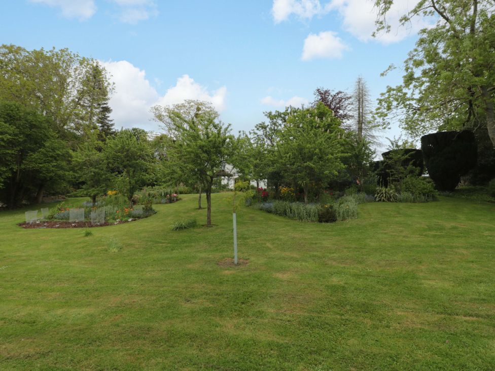 A garden with trees and flower beds at Stowey Mead Stables in Bishop Sutton