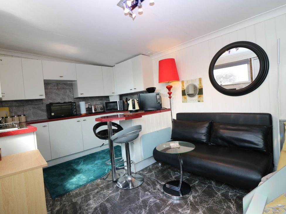 A kitchen with a sofa and bar stools at The Cabin in East Wemyss near Buckhaven