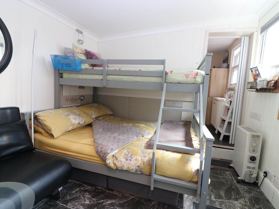 A bedroom with a bunk bed and a sofa at The Cabin in East Wemyss near Buckhaven