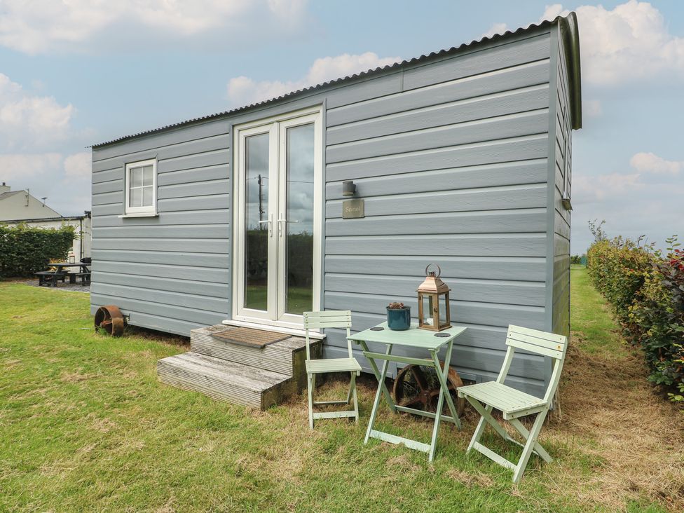 An outdoor seating area with a table and chairs at Seiriol Shepherds hut Ty Croes