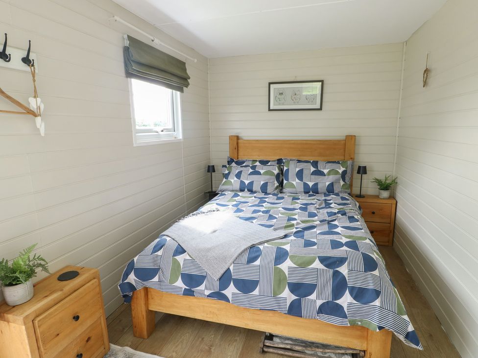 A bedroom with a bed and bedside table at Seiriol Shepherds hut in Ty Croes
