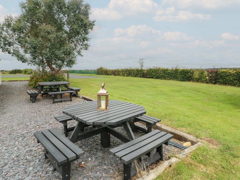 A garden with a table and benches at Seiriol Shepherds hut Ty Croes