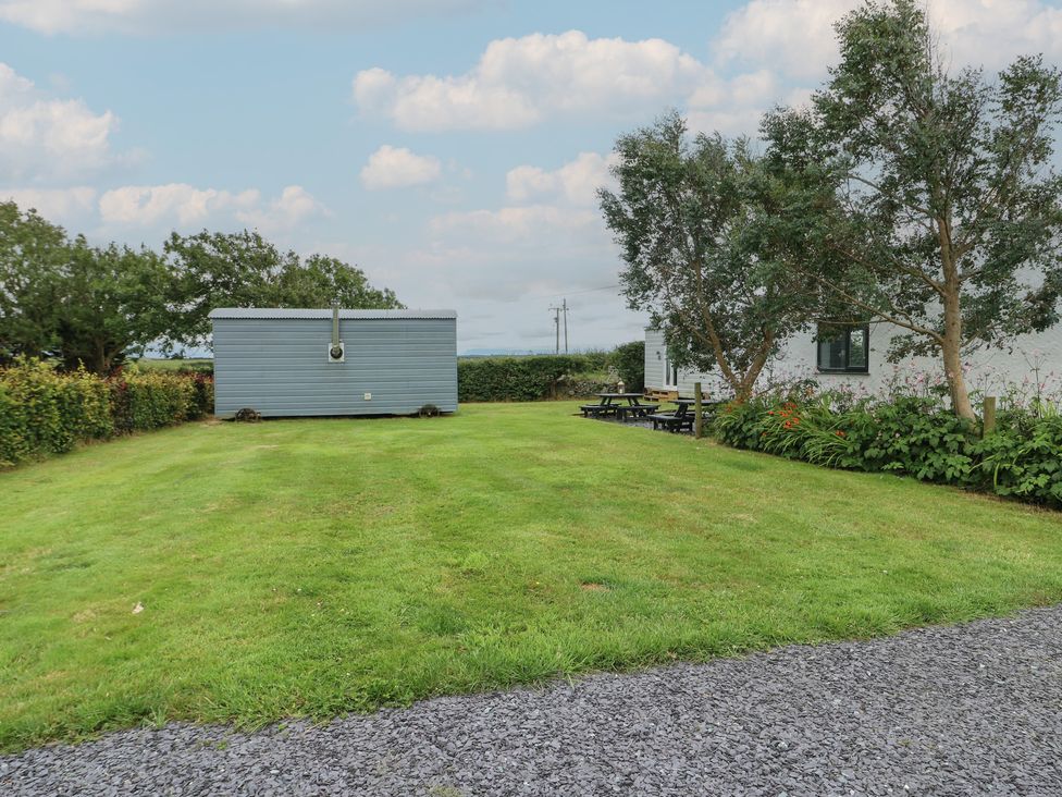 An outdoor area with a shepherd's hut and seating at Seiriol Shepherds hut Ty Croes