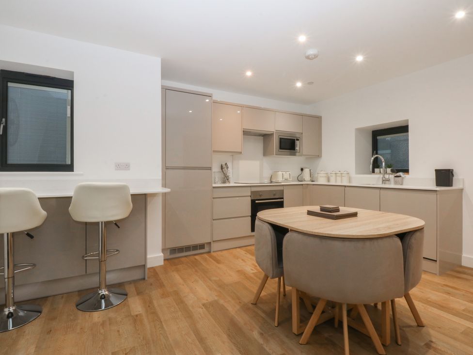 A kitchen with bar stools and a dining table at 2 Harbour Lights in Cemaes Bay