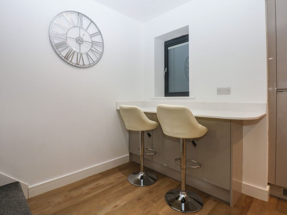 A kitchen with a clock and bar stools at 2 Harbour Lights Cemaes Bay