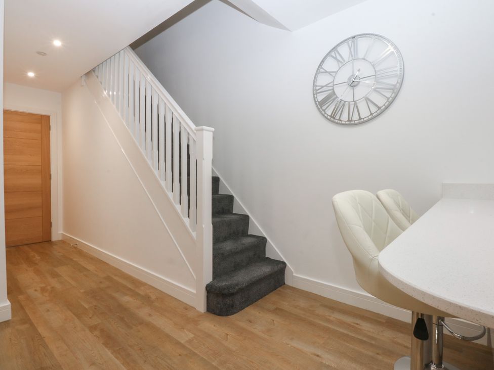A hallway with a staircase and clock at 2 Harbour Lights in Cemaes Bay