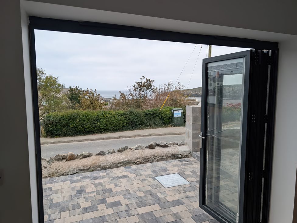 A view from a doorway showing pavement and greenery at 2 Harbour Lights, Cemaes Bay
