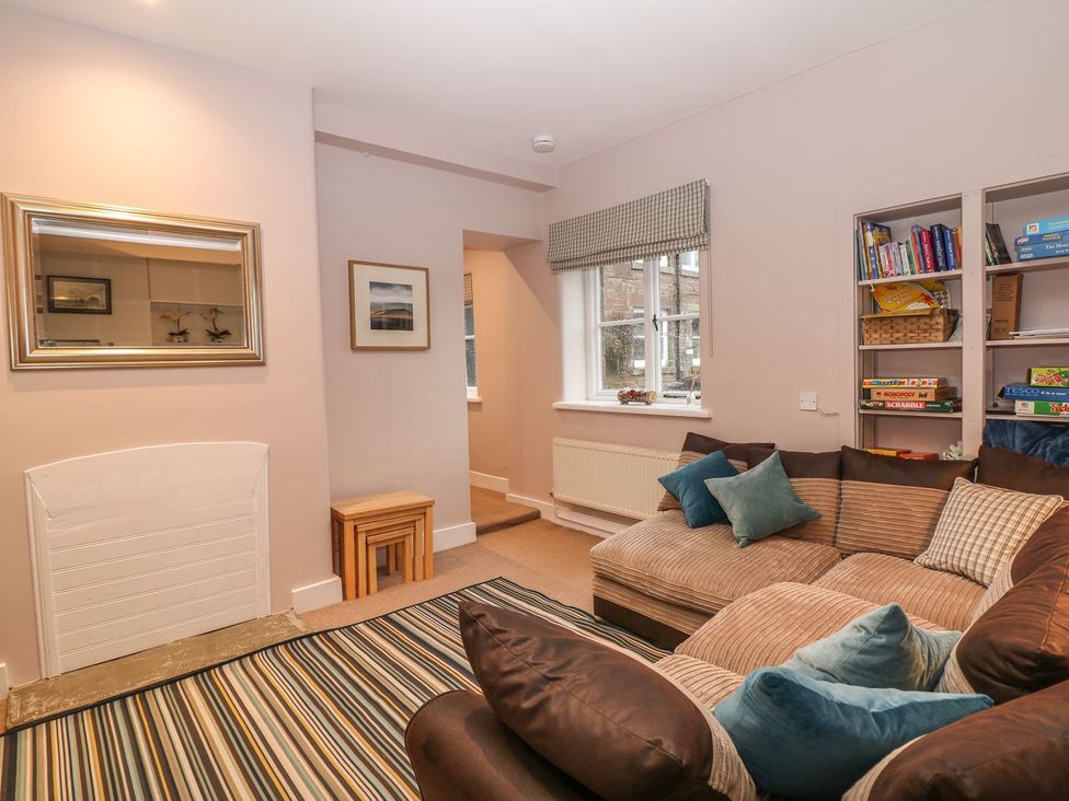 A living room with a sofa, mirror, and bookshelf at The Bothy in Wildboarclough