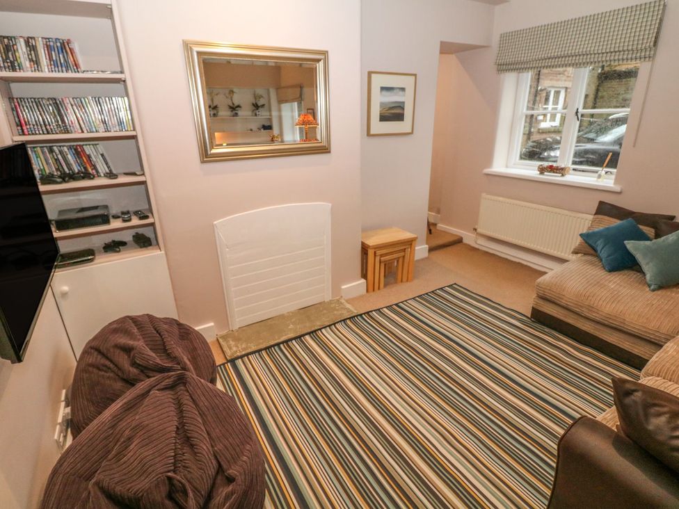 A living room with a TV, couch, bean bags, and a rug at The Bothy in Wildboarclough