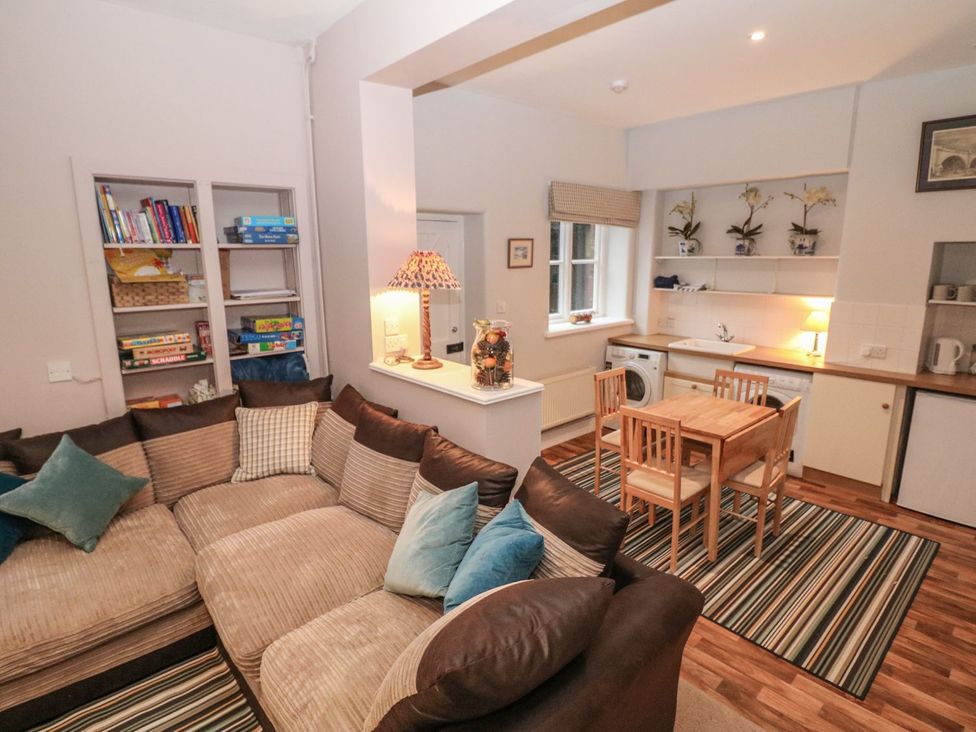 A living room with a sofa and kitchen area at The Bothy in Wildboarclough