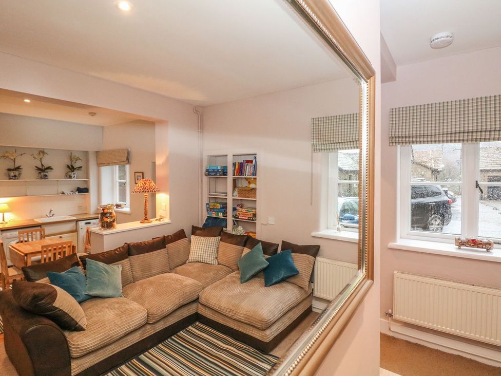 A living room with a sofa and bookshelves at The Bothy in Wildboarclough