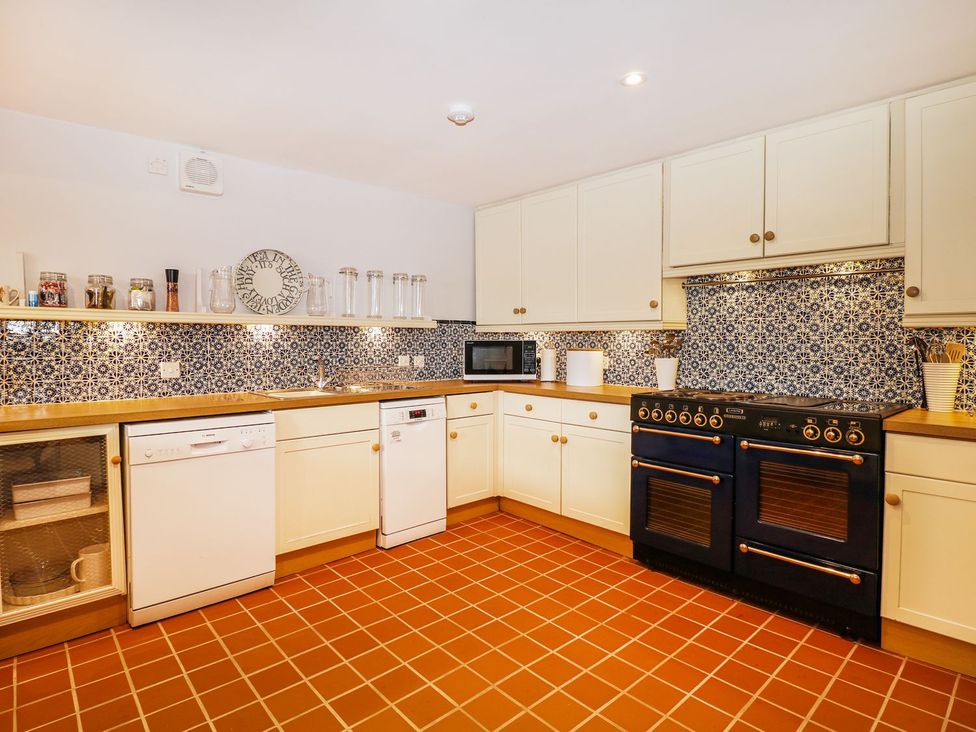 A kitchen with cabinets stove and microwave at The Bothy in Wildboarclough
