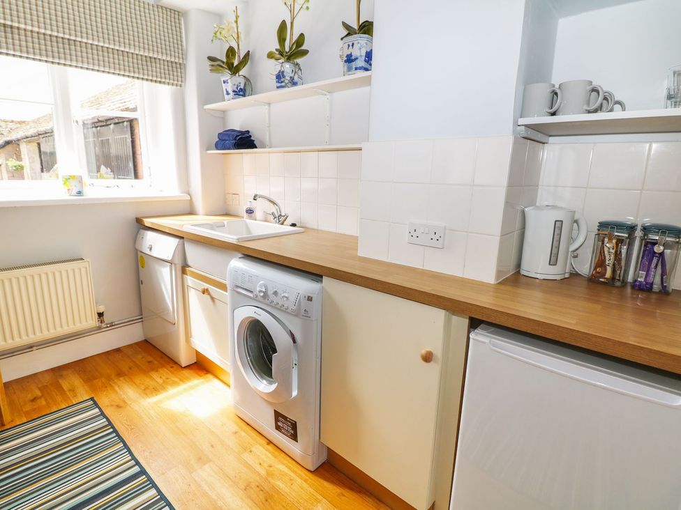 A kitchen with a sink and washing machine at The Bothy in Wildboarclough