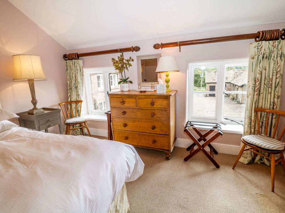 A bedroom with a chest of drawers and windows at The Bothy in Wildboarclough