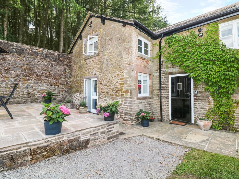 An exterior view of a stone cottage with planters at The Bothy in Wildboarclough