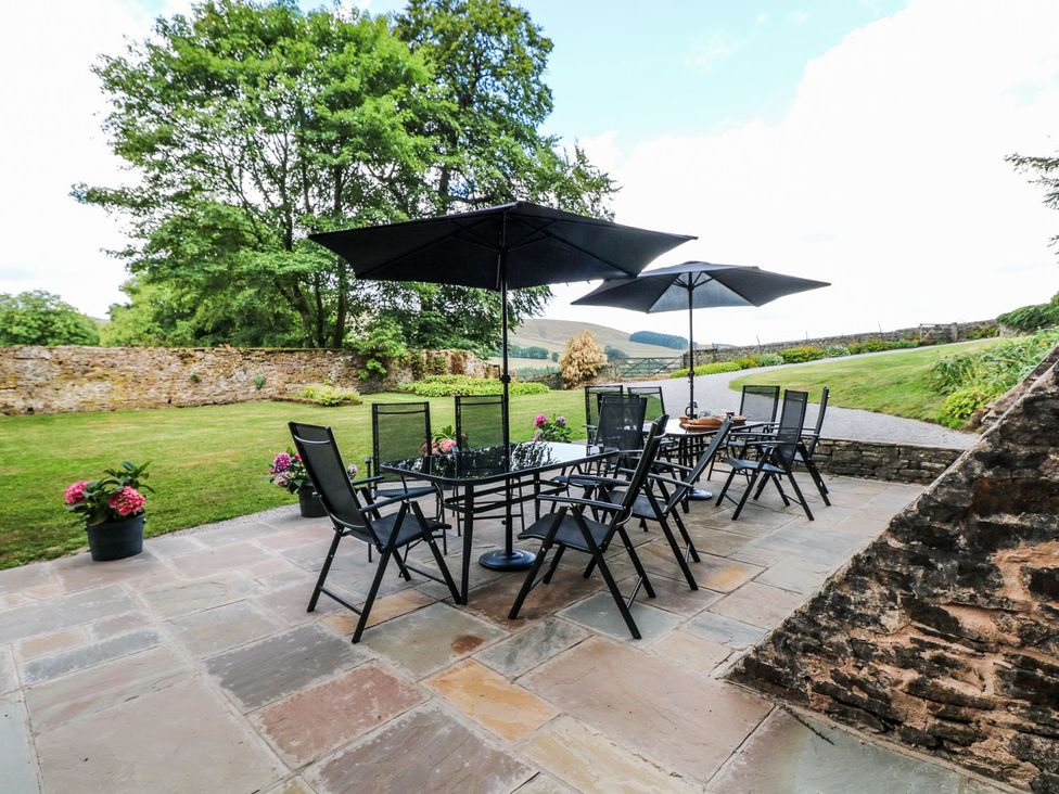 An outdoor seating area with a table, chairs, and umbrellas at The Bothy in Wildboarclough