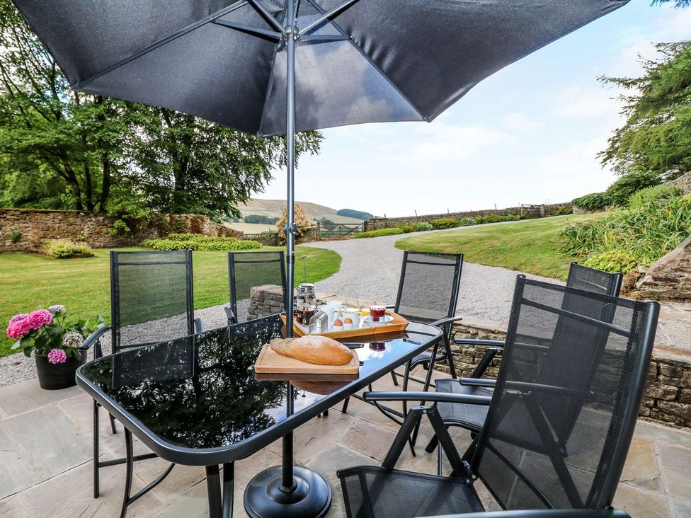 An outdoor seating area with a table and chairs at The Bothy in Wildboarclough