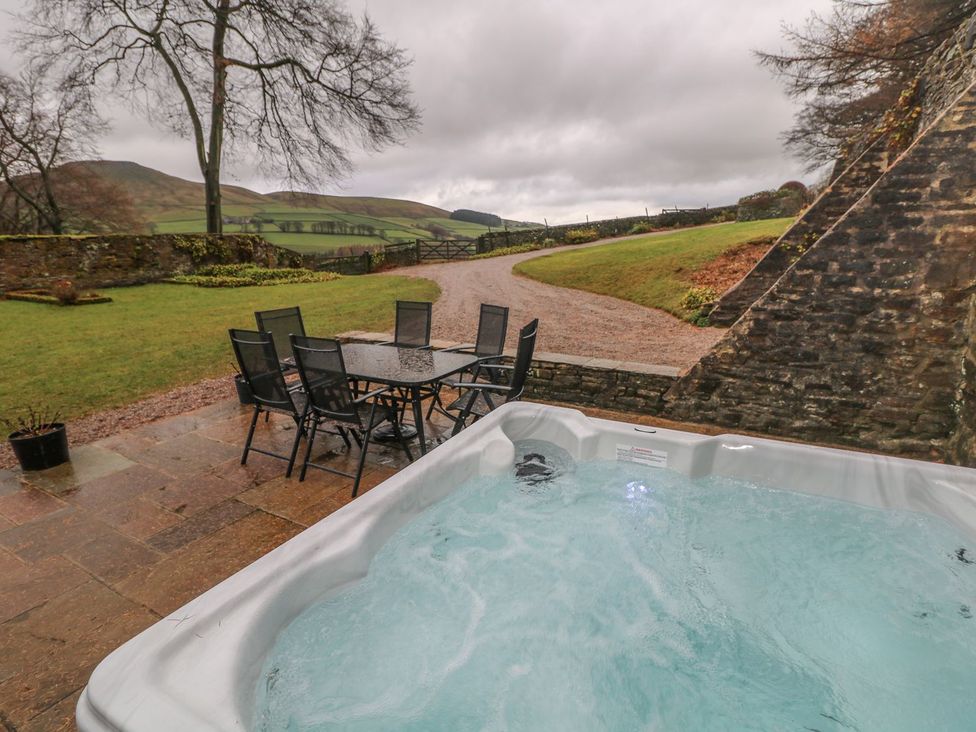 An outdoor area with a hot tub and a dining table at The Bothy in Wildboarclough