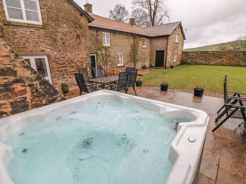 An outdoor area with a hot tub and seating at The Bothy in Wildboarclough
