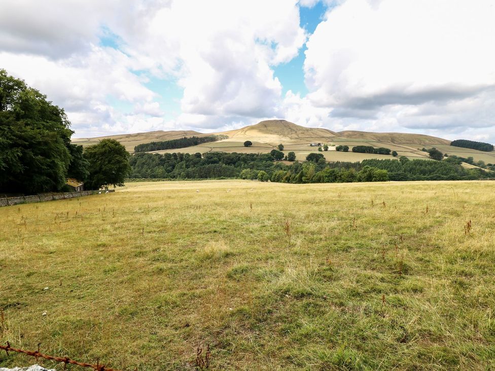 A scenic field with trees and hills at The Bothy in Wildboarclough