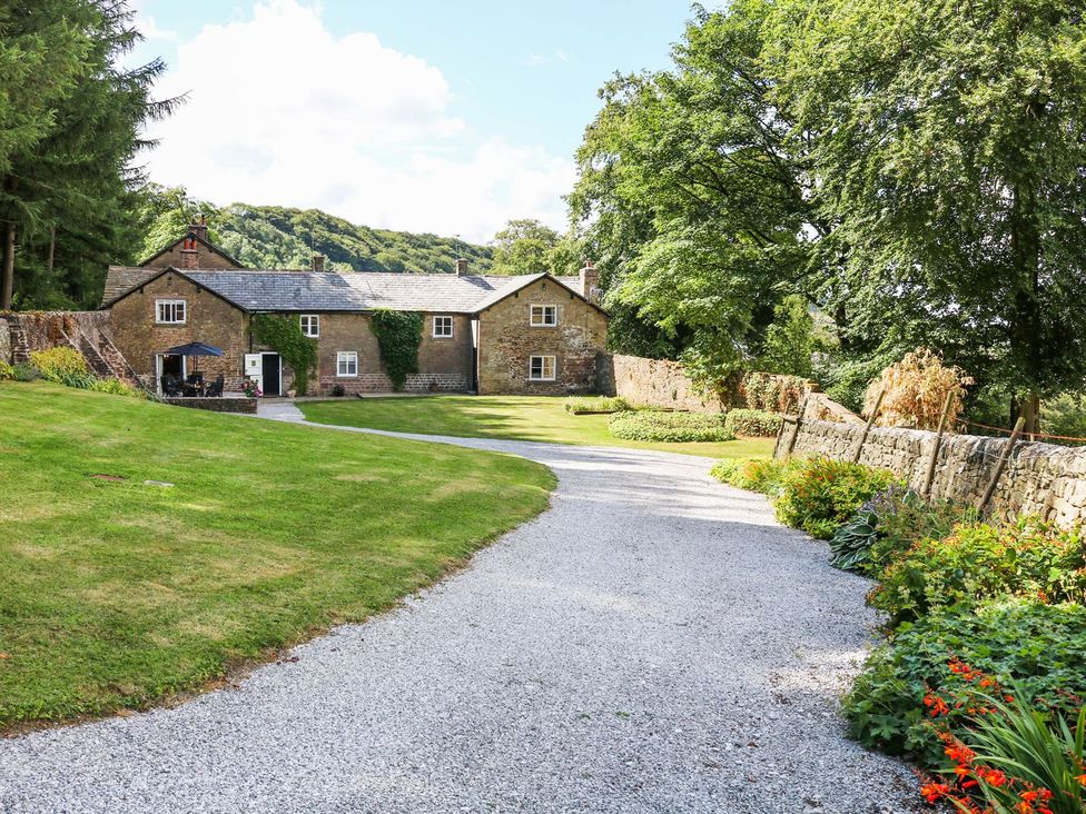 An outdoor view of a house with a gravel driveway and landscaped garden at The Bothy in Wildboarclough