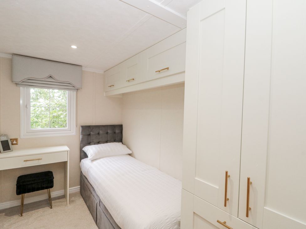 A bedroom with a bed, desk, and wardrobe at The Cabin in Thornton Dale