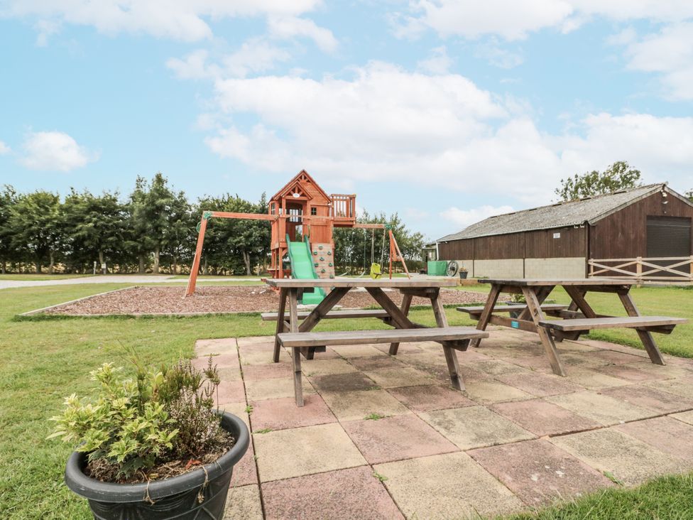 An outdoor area with a play structure and picnic tables at The Cabin in Thornton Dale