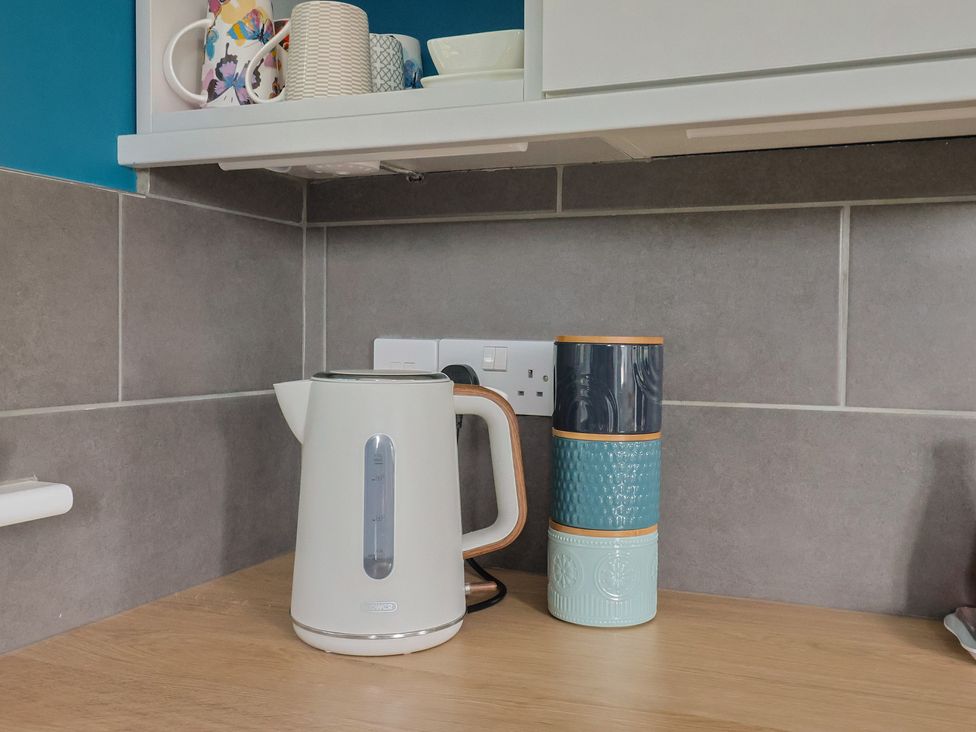 A kettle and stacked mugs on a countertop at The Roost in Whitford Nr. Colyton
