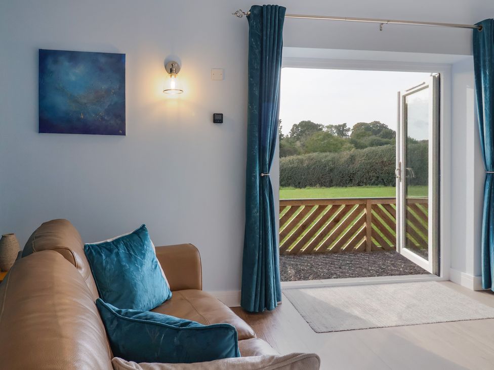 A living room with a couch and open door at The Roost in Whitford Nr. Colyton