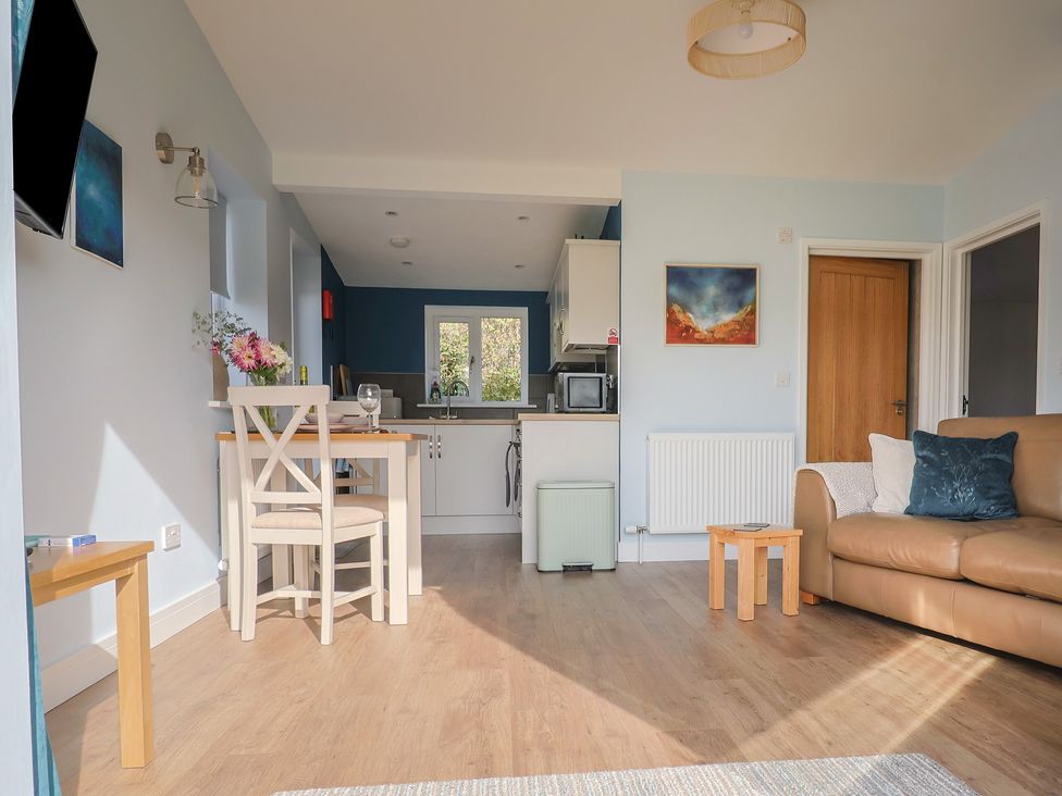 A living room with a sofa and kitchen area at The Roost in Whitford Nr. Colyton