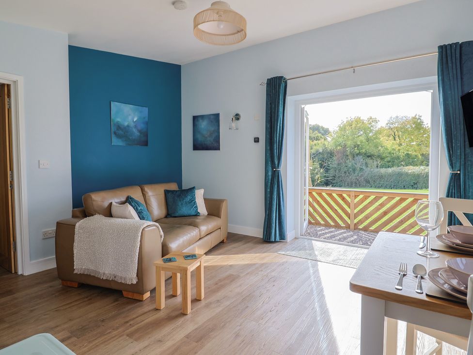 A living room with a sofa and dining area at The Roost in Whitford Nr. Colyton
