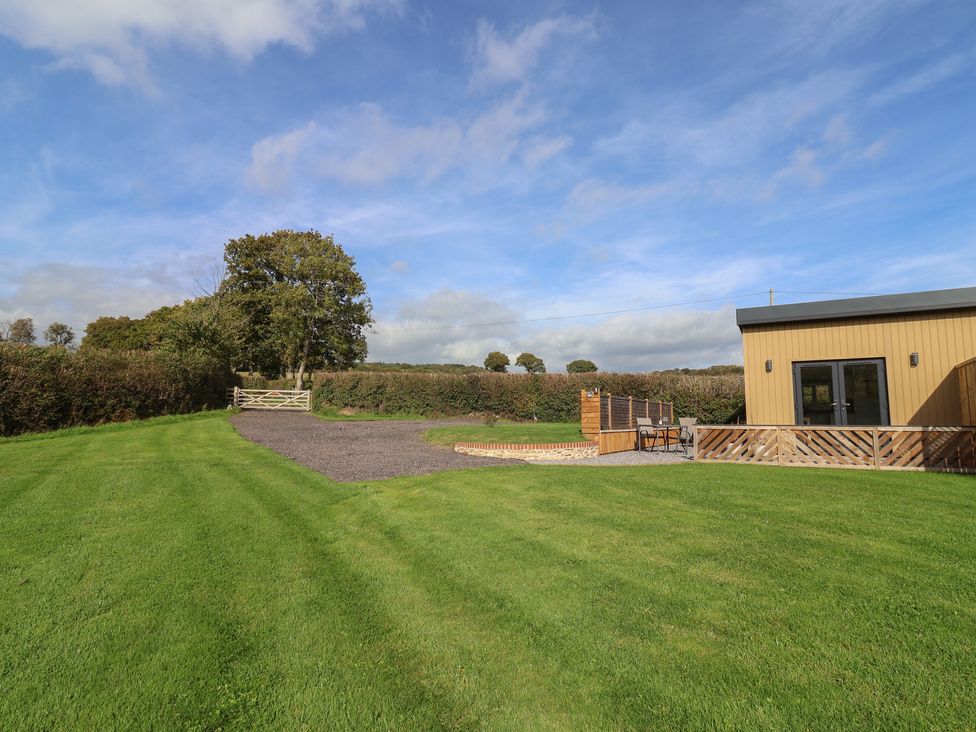 An outdoor area with a building, gate, and seating at The Roost Whitford Nr. Colyton