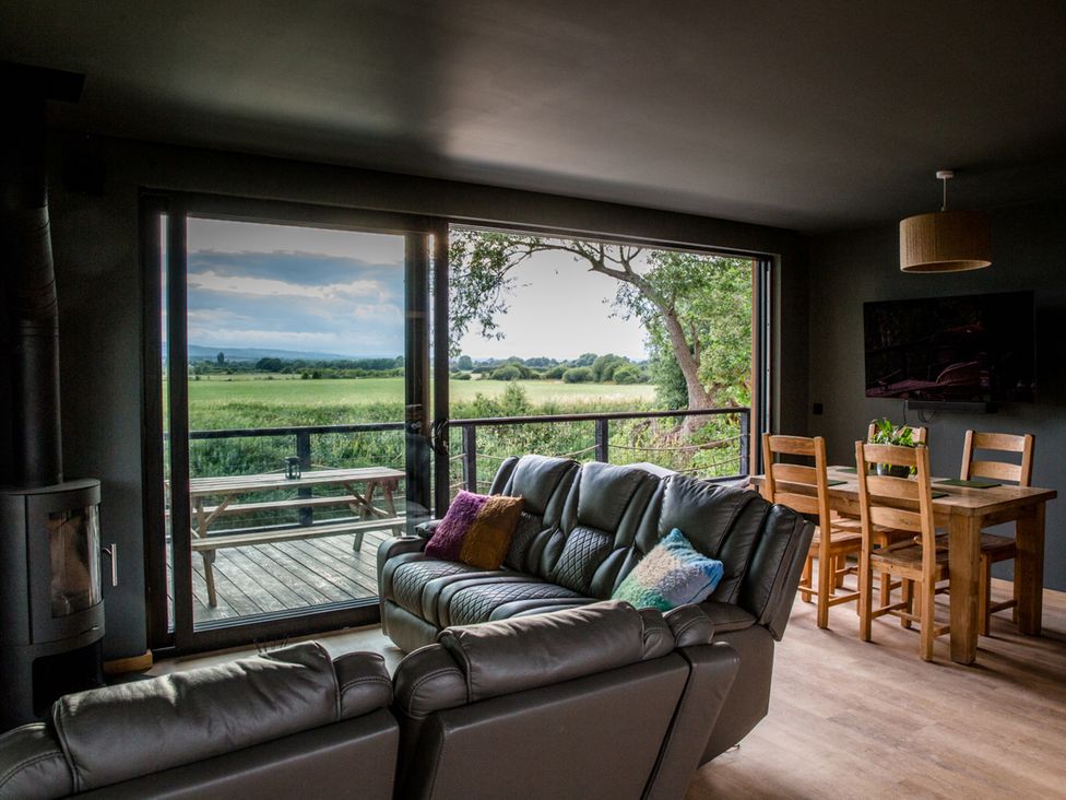A living room with a sofa and dining area overlooking a view at The Red House in Farndon