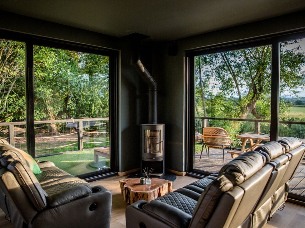 A living room with a wood stove and large windows at The Red House in Farndon