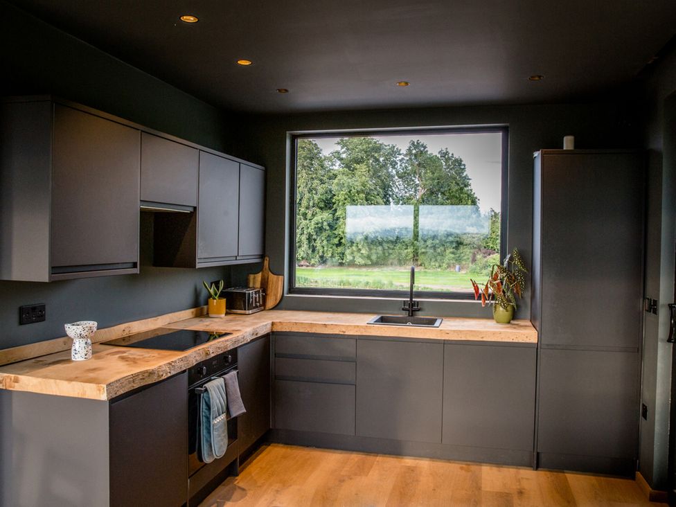 A kitchen with modern cabinets and a large window at The Red House in Farndon