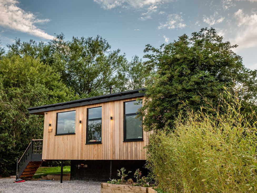 A wooden house with windows and stairs surrounded by greenery at The Red House in Farndon