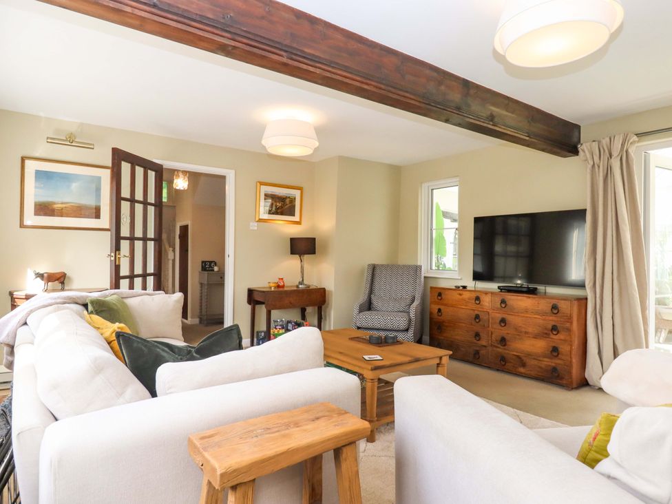 A living room with a TV and seating arrangements at Town Farm Cottage in Barnstaple