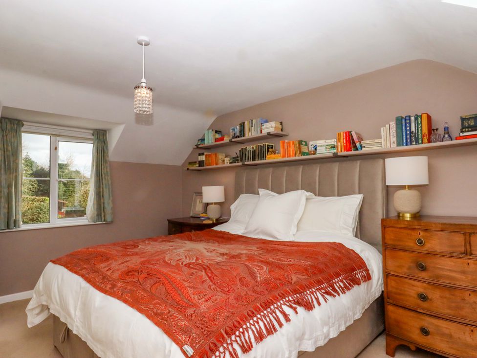 A bedroom with a bed and books on a shelf at Town Farm Cottage in Barnstaple