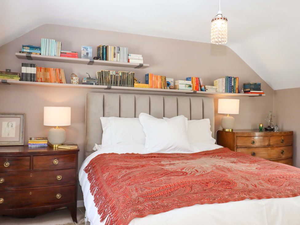 A bedroom with a bed and bookshelves at Town Farm Cottage in Barnstaple