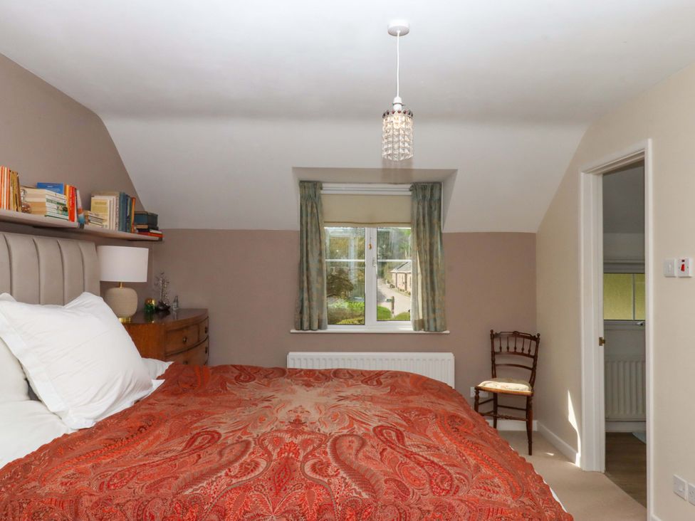 A bedroom with a bed and bookshelf at Town Farm Cottage in Barnstaple